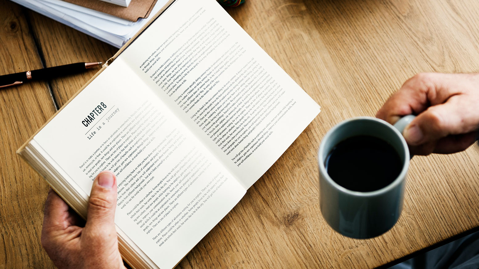 Person reading a book while drinking coffee